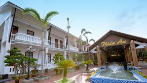 A hotel with a traditional architectural style, featuring a central courtyard with a fountain, potted plants, and a tiled walkway. - Thien An Hotel (Can Tho)