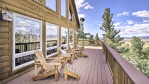 A wooden deck with Adirondack chairs and large windows overlooking a scenic landscape. - Quiet Fairplay Cabin w/ Rocky Mountain Views! (Fairplay)