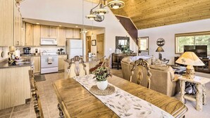 A spacious kitchen with wooden cabinets, a dining area with a wooden table, and a living room with a sofa and TV. - Quiet Fairplay Cabin w/ Rocky Mountain Views! (Fairplay)
