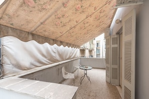 A balcony with a floral awning, a small table, two chairs, and a view of buildings in the background. - Athens Empire Paradise Apartment (Athens)