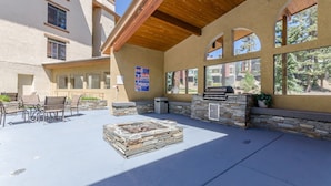 An outdoor patio with stone seating, a fire pit, and a grill area.