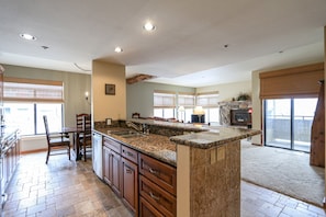 A spacious kitchen with granite countertops, wooden cabinets, and a large island.