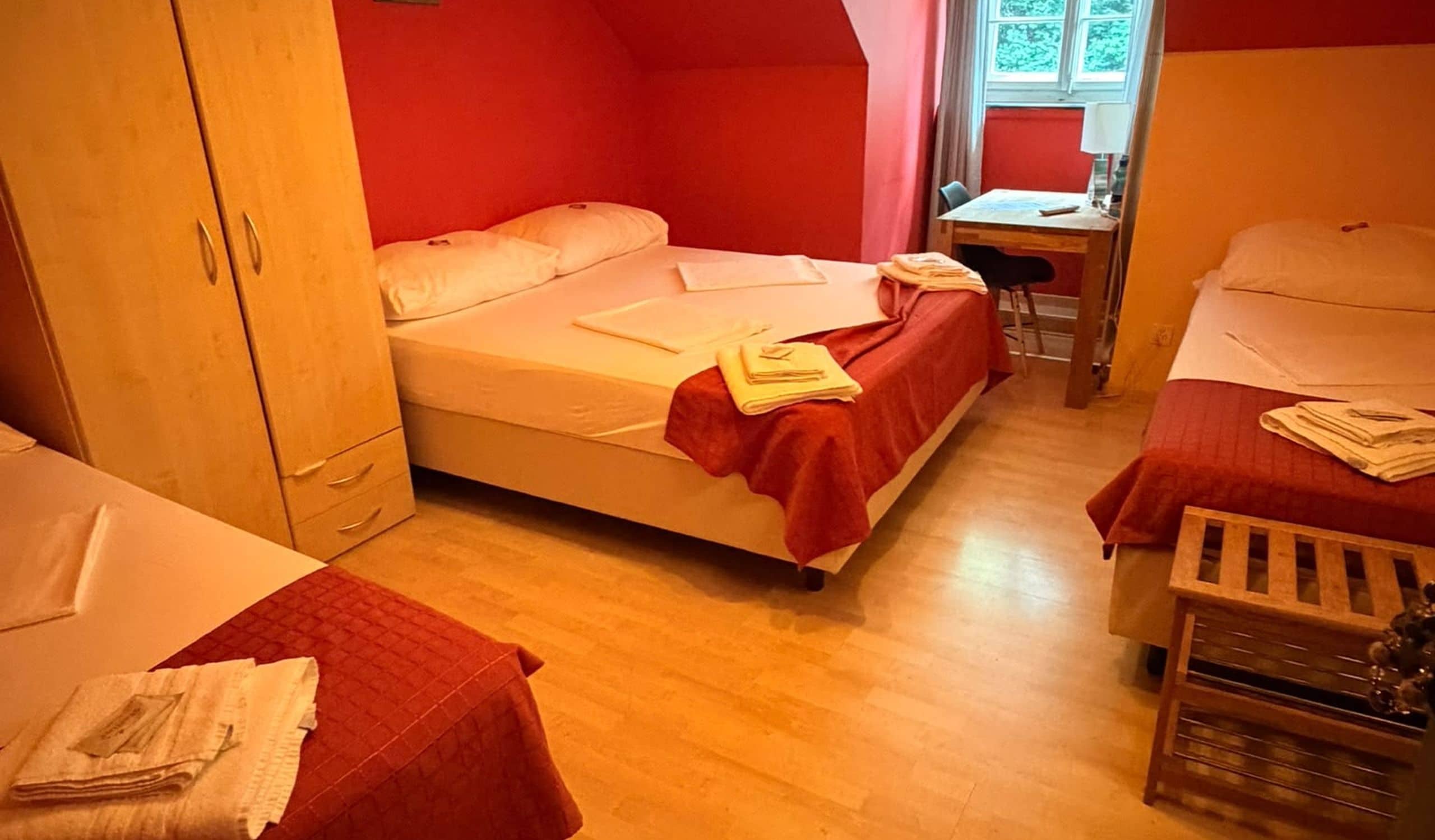 Une petite pièce, de taille modeste, comprenant deux lits, un bureau et une armoire.