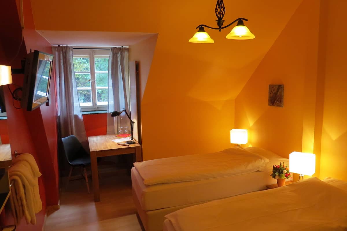 Una habitación de hotel con dos camas, un escritorio, una silla y un televisor.