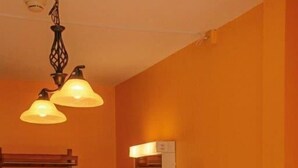 Habitación de hotel con dos camas, un banco de madera, un lavamanos, un espejo y una lámpara colgante.