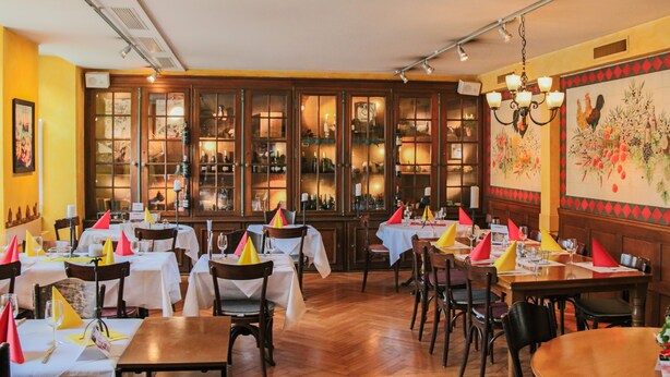 Un restaurante con mesas y sillas de madera, un candelabro y un mural grande en la pared.