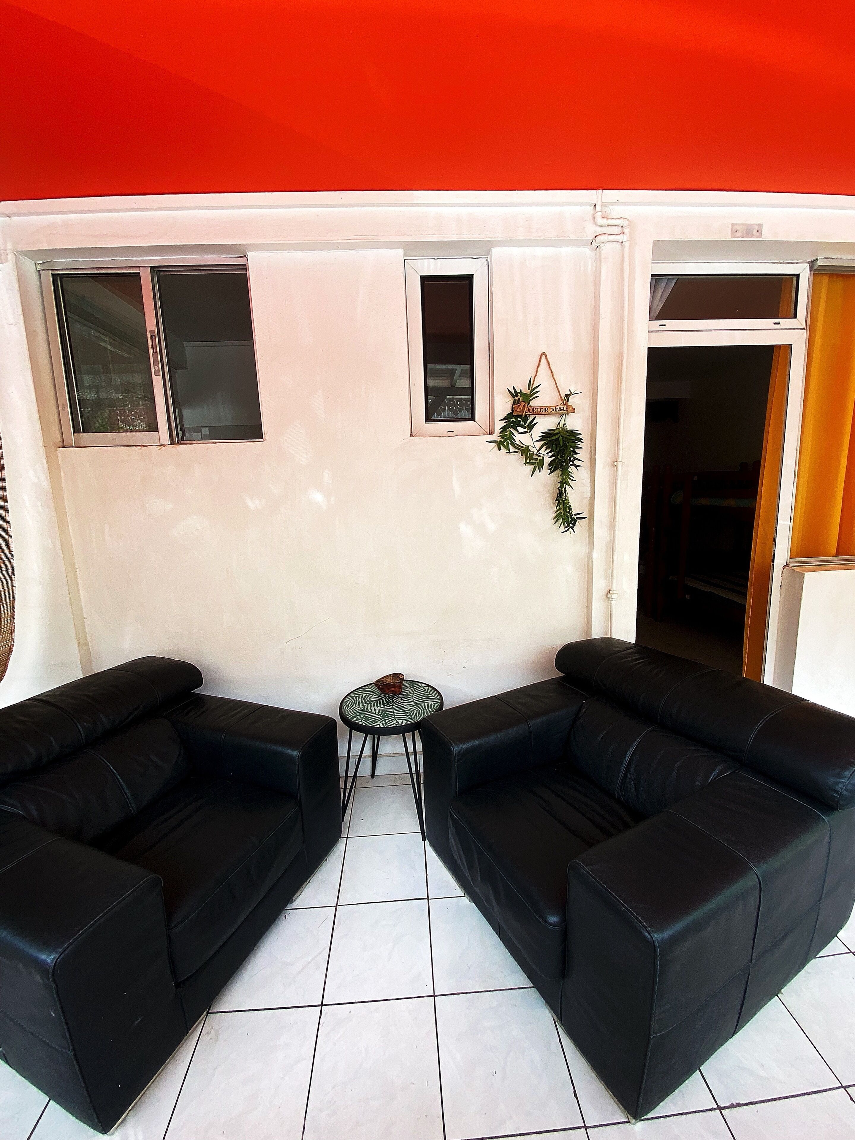 A room with two black leather sofas, a small round table, and a window with a view.