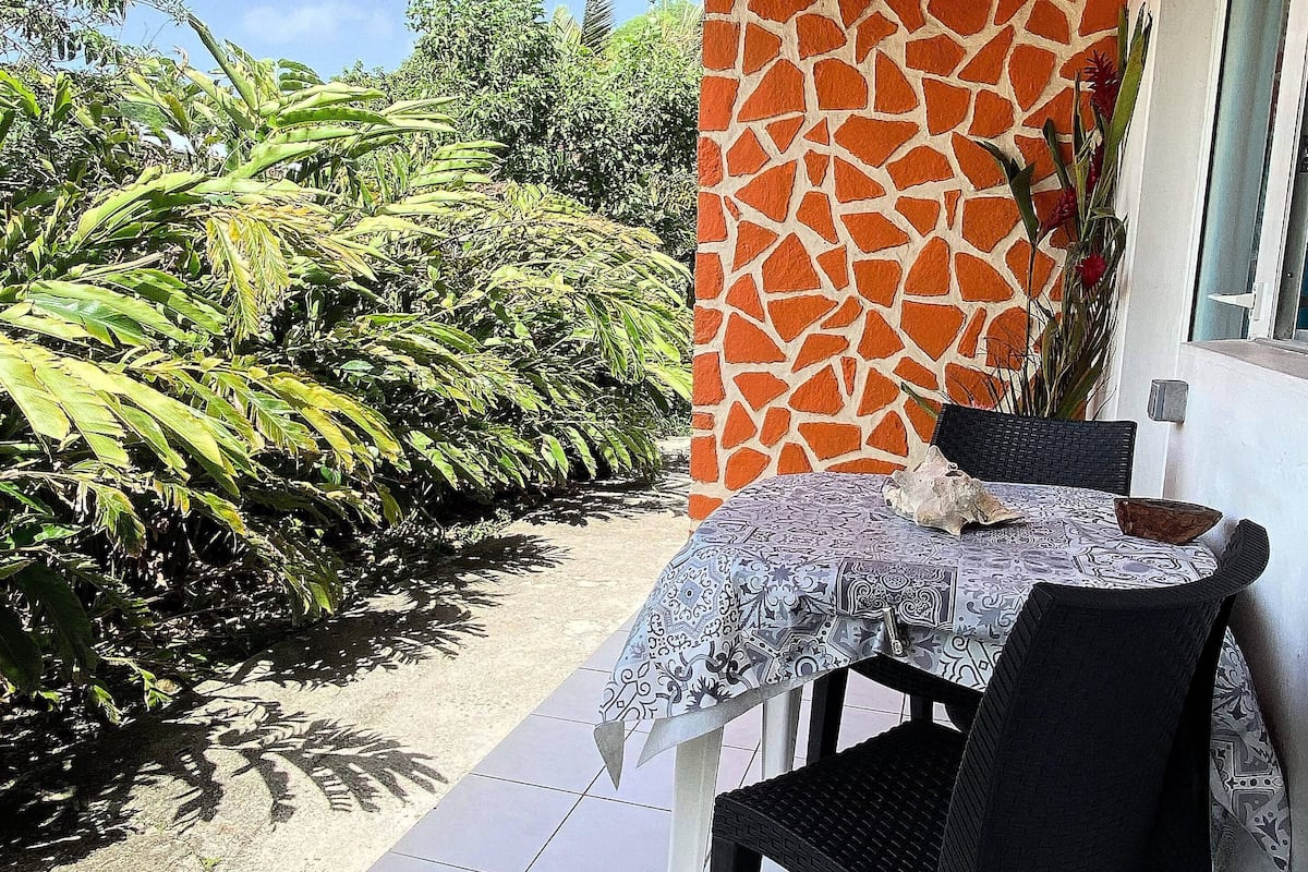 Um pátio com mesa e cadeiras, chão de azulejos e parede com padrão de girafa.
