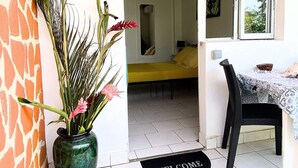 A room with a bed, a dining table, and a potted plant by the door. - Auberge K-Wan Hostel (Deshaies)