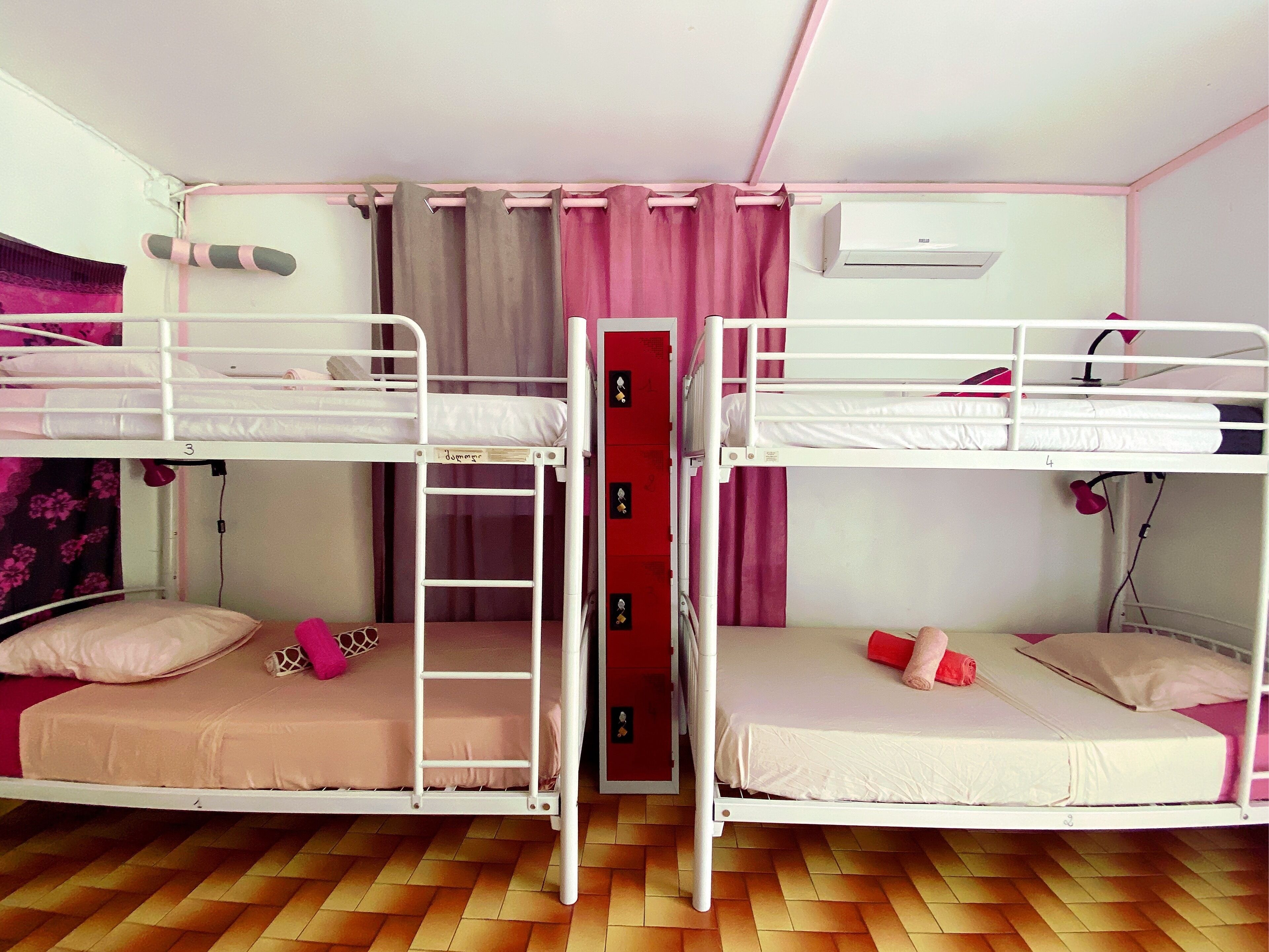 A bunk bed room with two beds, a ladder, a red cabinet, and a ceiling fan.