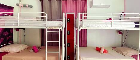 A bunk bed room with two beds, a ladder, a red cabinet, and a ceiling fan.