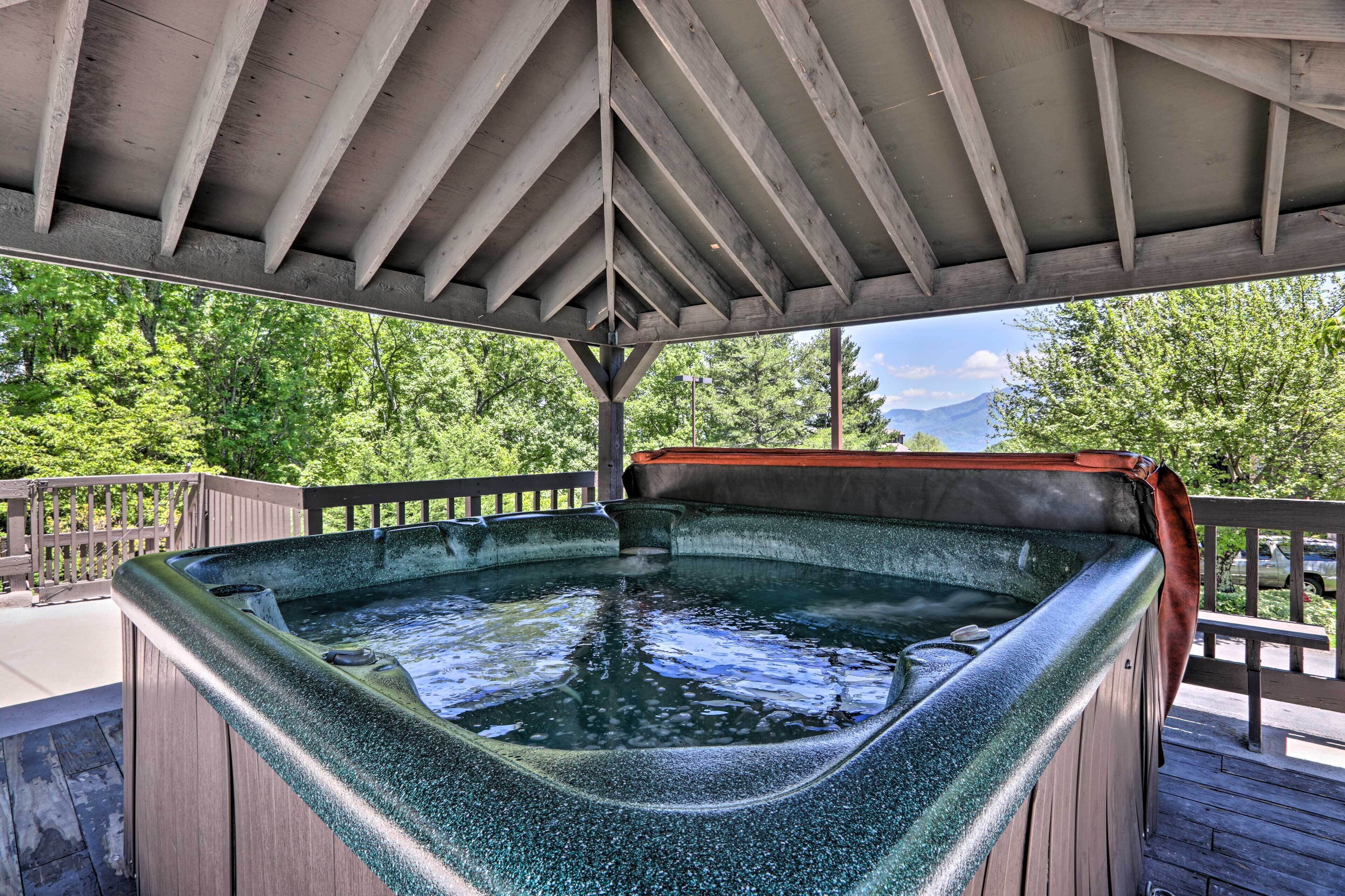 Un bain à remous sous une pergola en bois, avec vue sur les arbres et les montagnes.