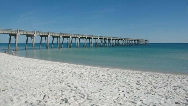 Een strand met een lange pier die zich uitstrekt in de oceaan.
