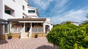 A modern two-story building with a tiled roof and a balcony with potted plants. - Apartments Karen (Marina)
