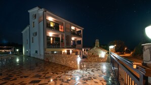 A multi-story building with balconies, a stone facade, and a tiled patio area. - Apartments Karen (Marina)