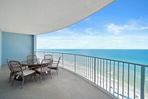 Een balkon met uitzicht op de oceaan, een ronde tafel met stoelen en een hekwerk.