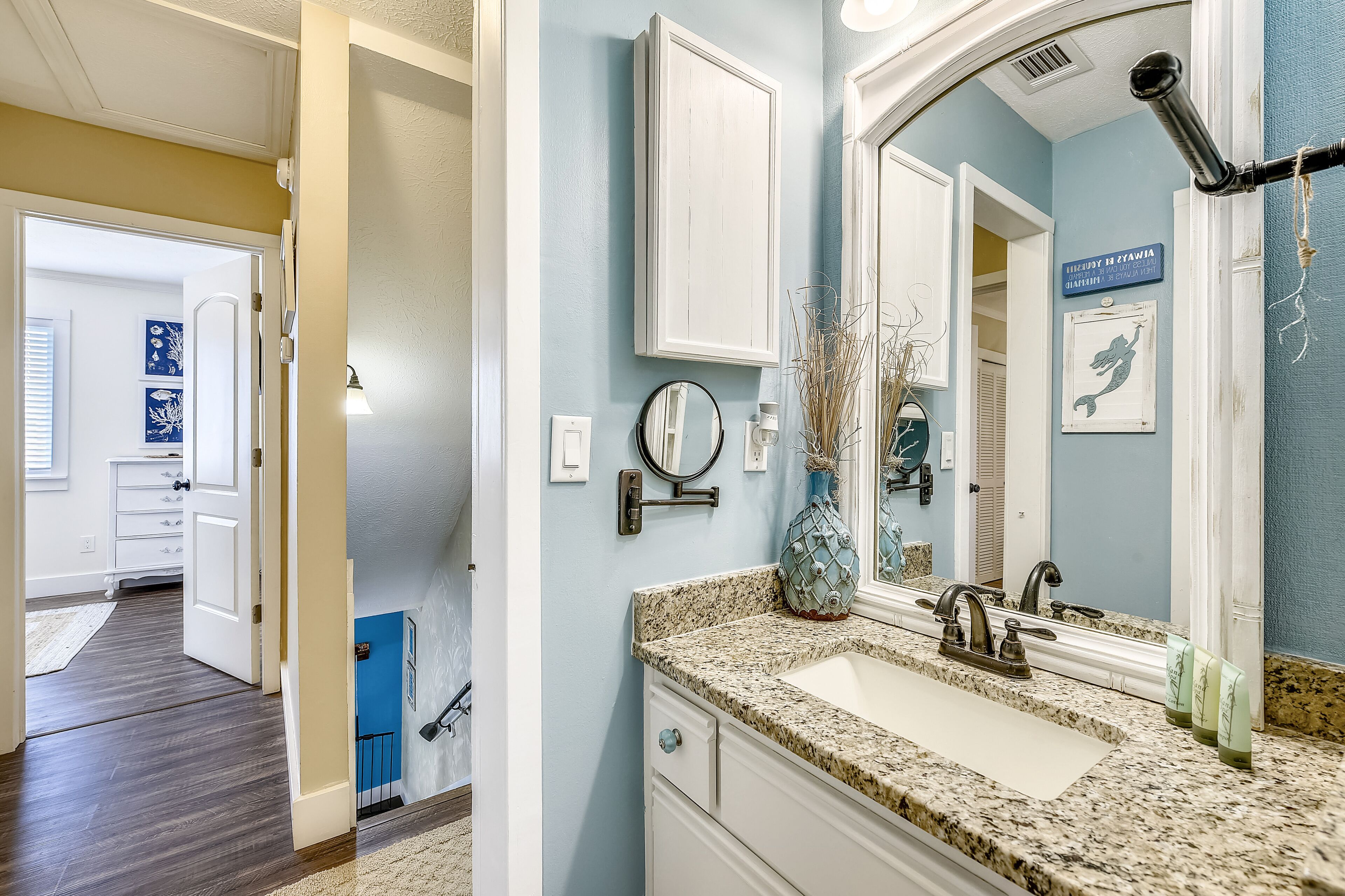 A bathroom with a granite countertop, a sink, a mirror, and a wall-mounted towel rack.