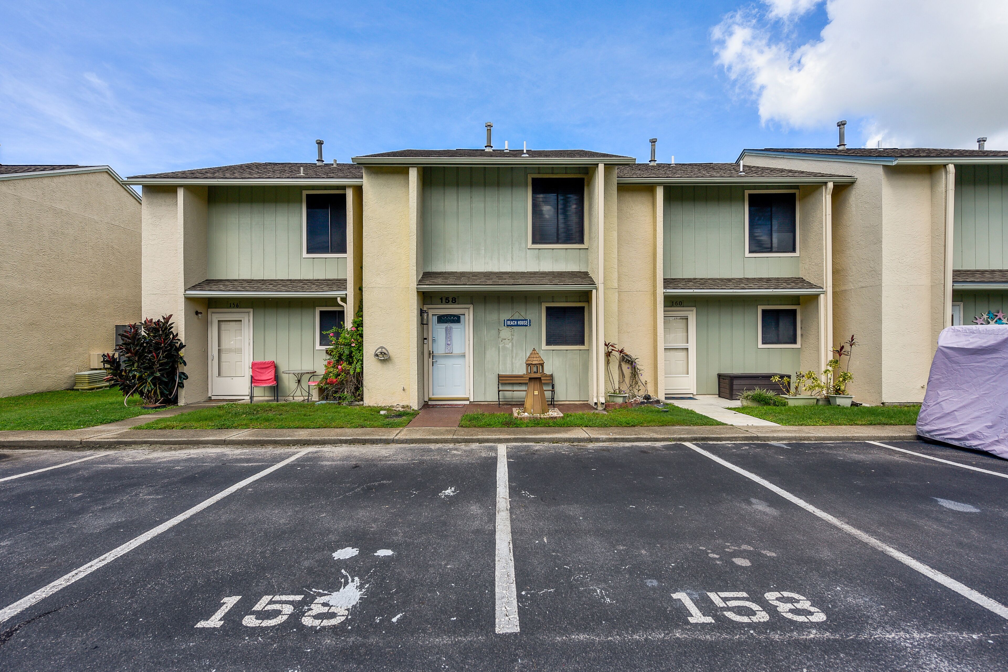 A row of townhouses with a parking lot in front, numbered 158.