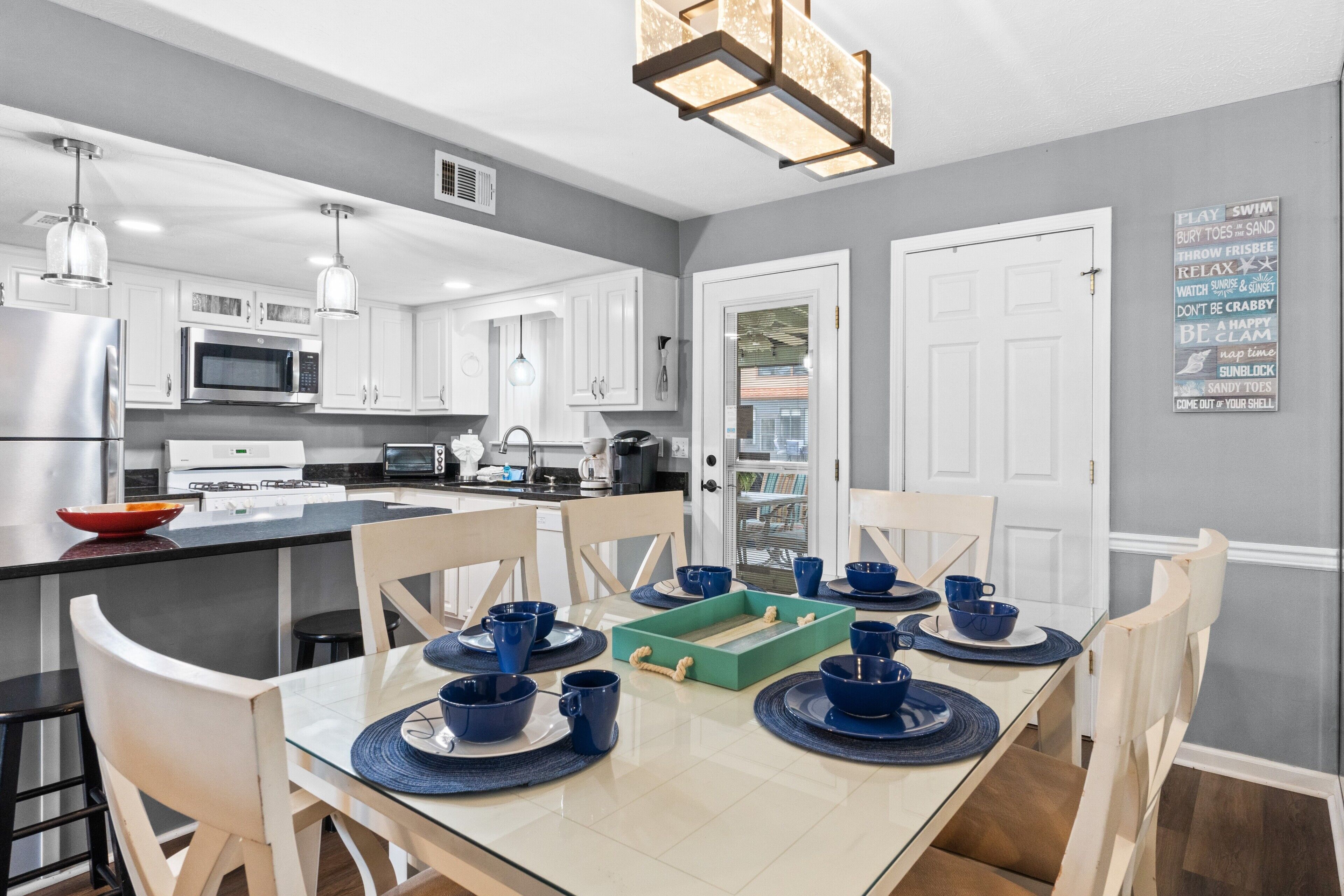 A modern kitchen with white cabinets, stainless steel appliances, and a dining area with a glass table set for four.