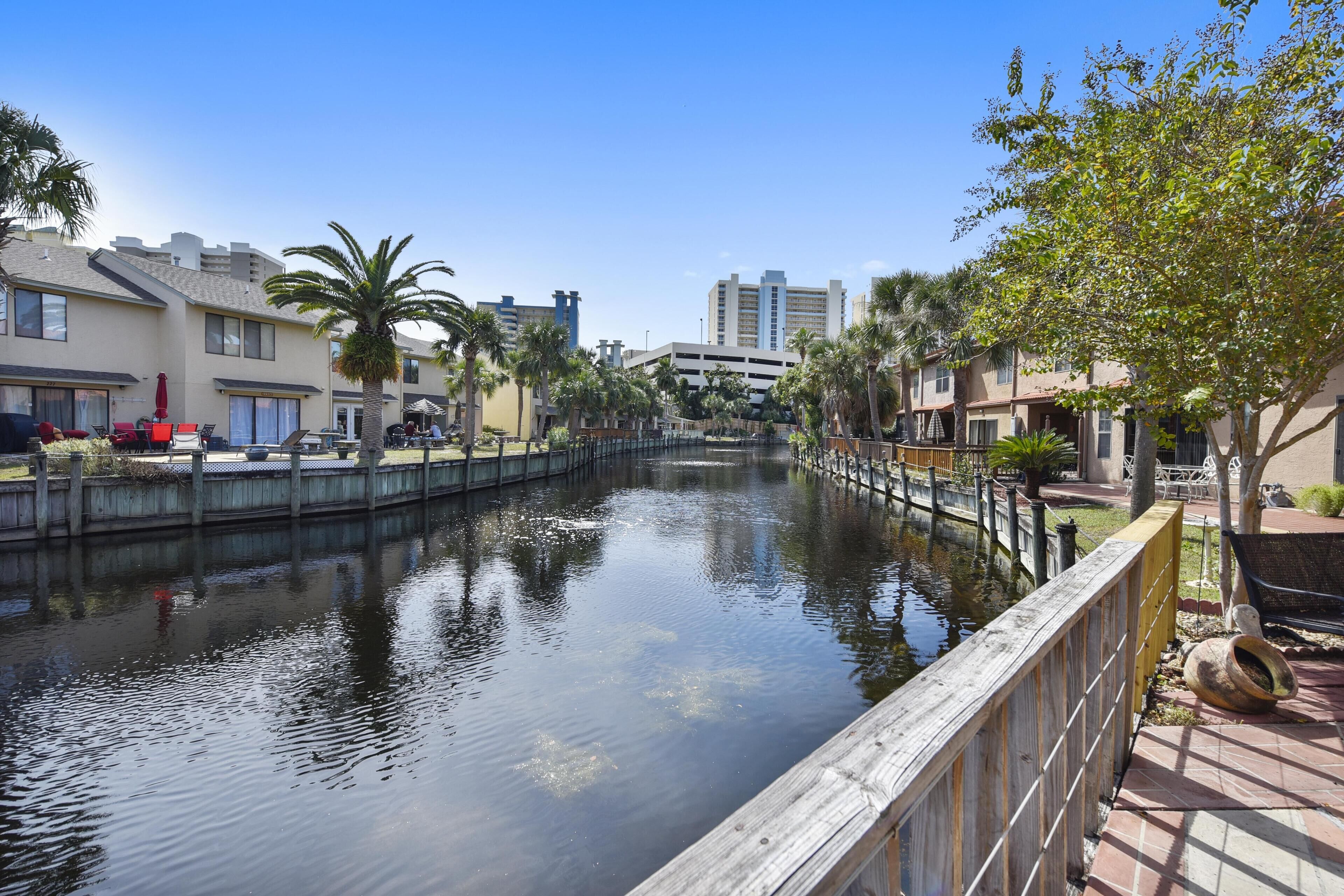 A canal with wooden walkways and palm trees, surrounded by residential buildings.