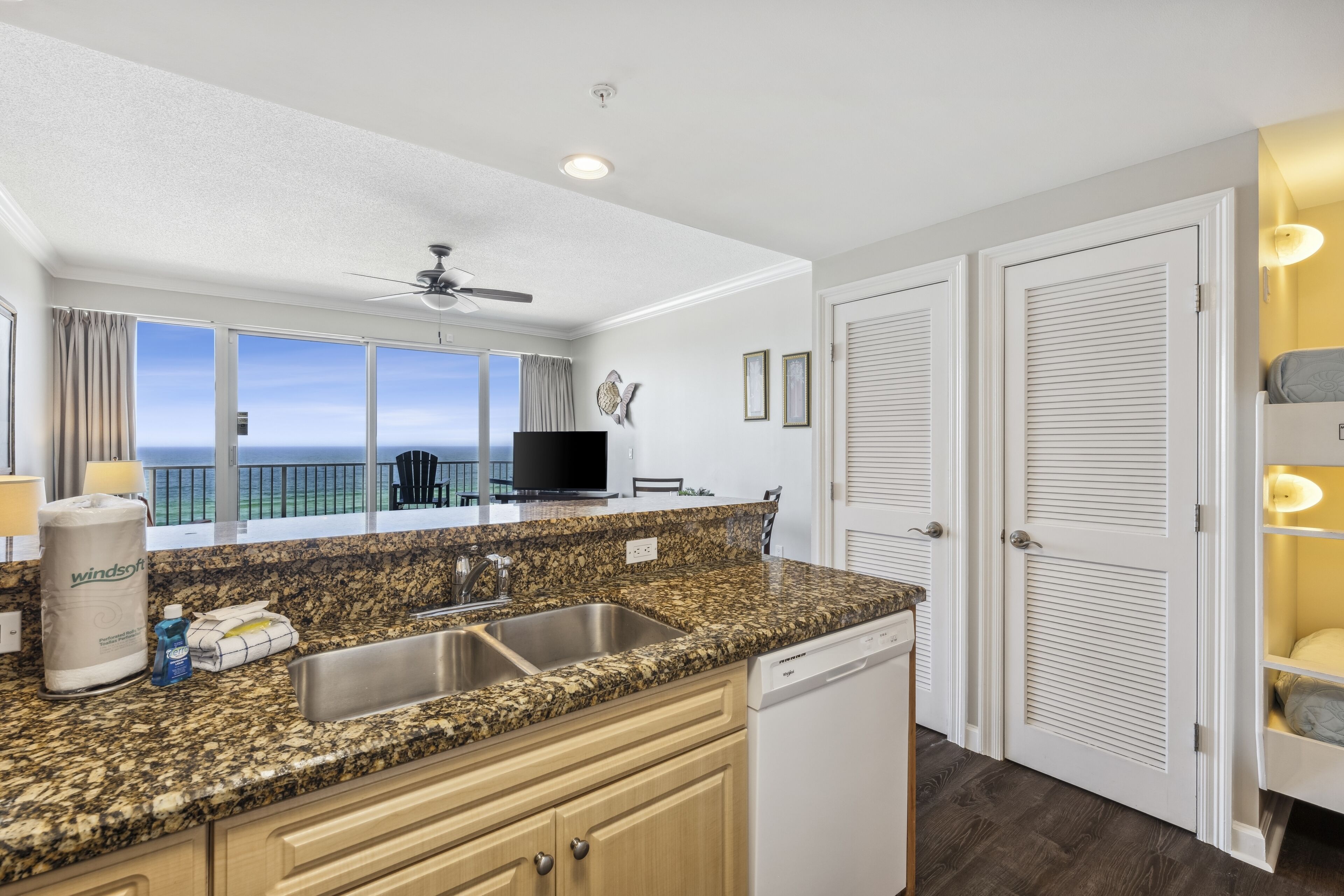 A kitchen with granite countertops, a built-in dishwasher, and a view of the ocean.