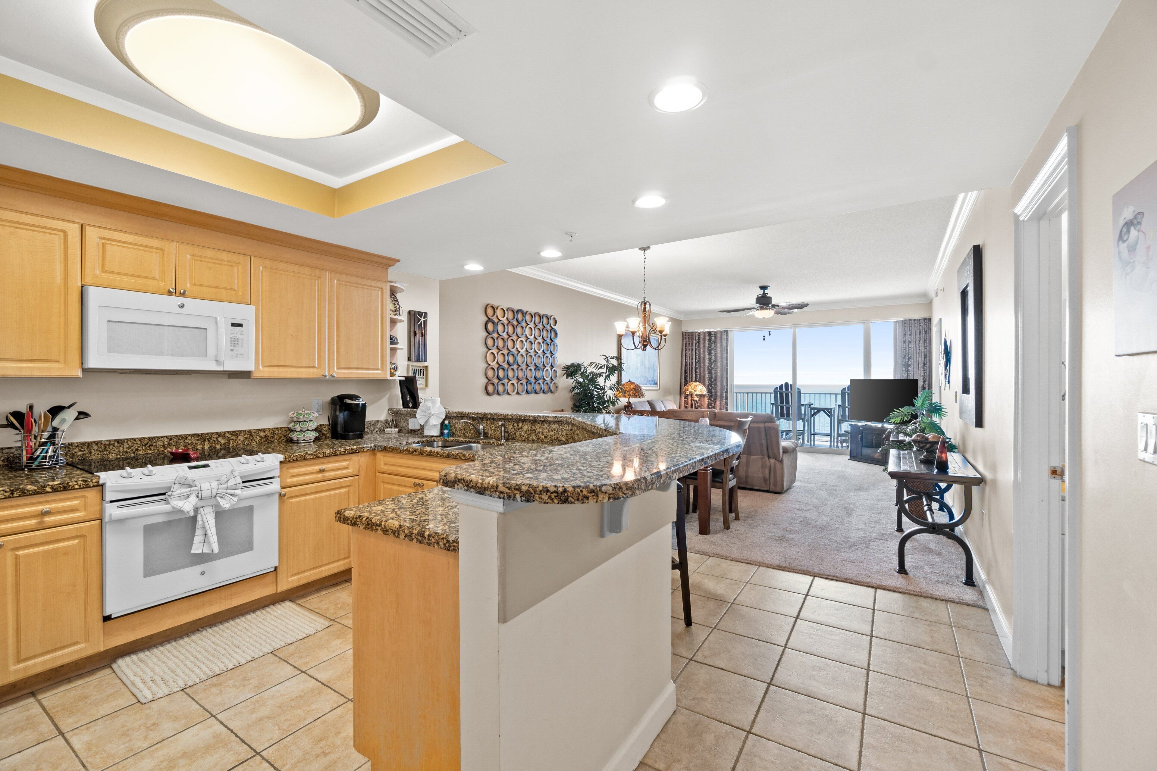 A modern kitchen with granite countertops, wooden cabinets, and a central island.