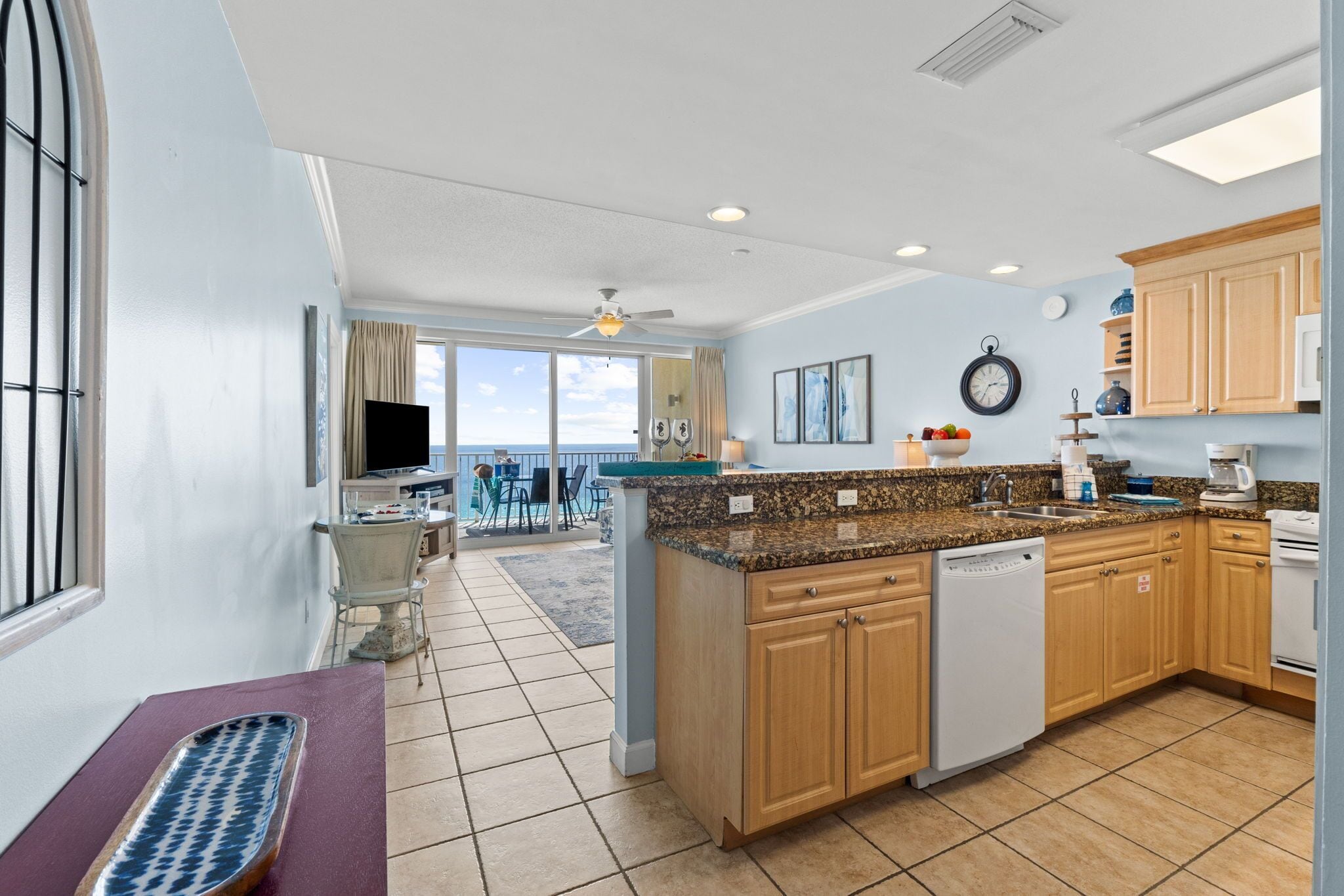 A modern kitchen with a central island, wooden cabinets, and a view to the outside.