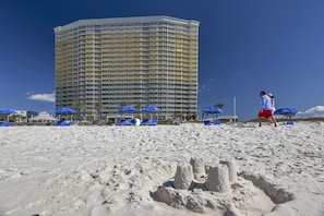 A beachfront hotel with a high-rise structure, beach umbrellas, and sandcastles. - Boardwalk Beach Resort by Book That Condo (Panama City Beach)