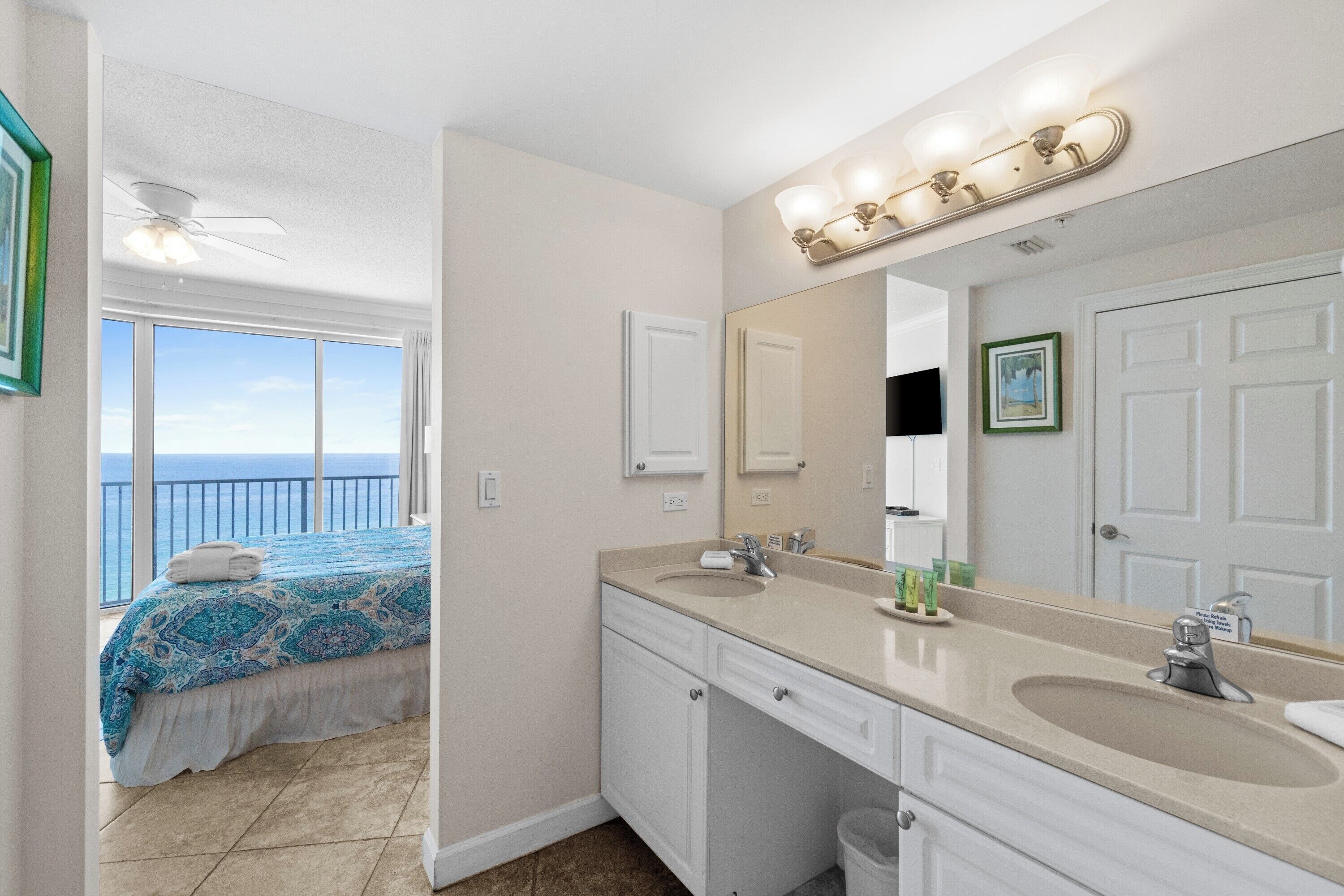 A bathroom with two sinks, a large mirror, and a ceiling fan.