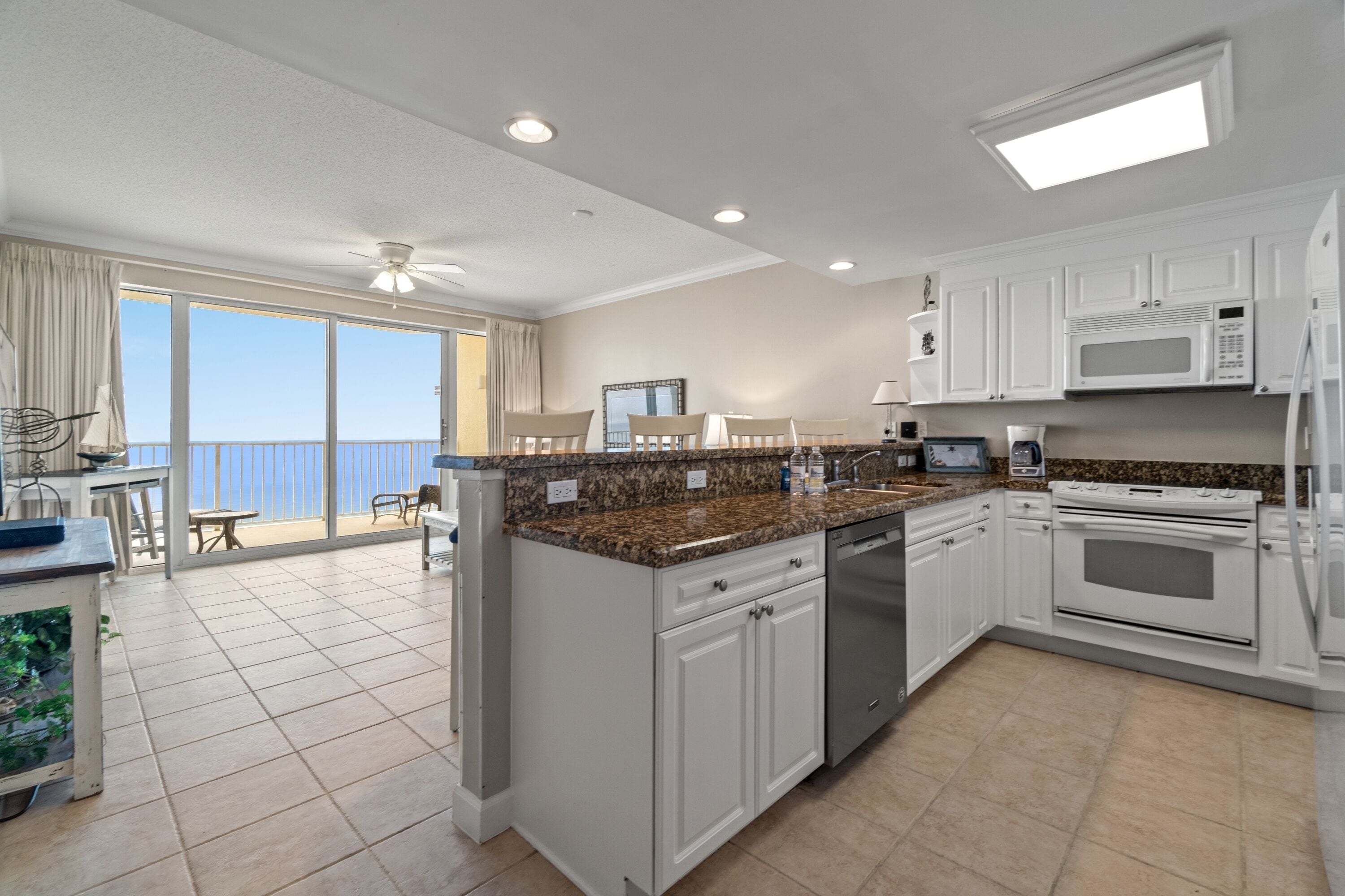 A modern kitchen with white cabinets, granite countertops, a built-in oven, and a microwave.