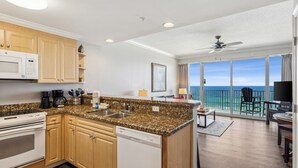 Eine moderne Küche mit Granit Arbeitsplatten, Holzschränken und einem Geschirrspüler. Sie führt zu einem Balkon mit Meerblick.