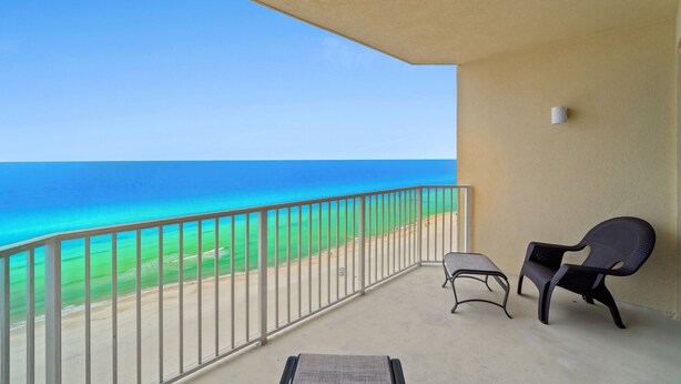 Ein Balkon mit Meerblick, ein Sessel, ein kleiner Tisch und eine Wandleuchte.