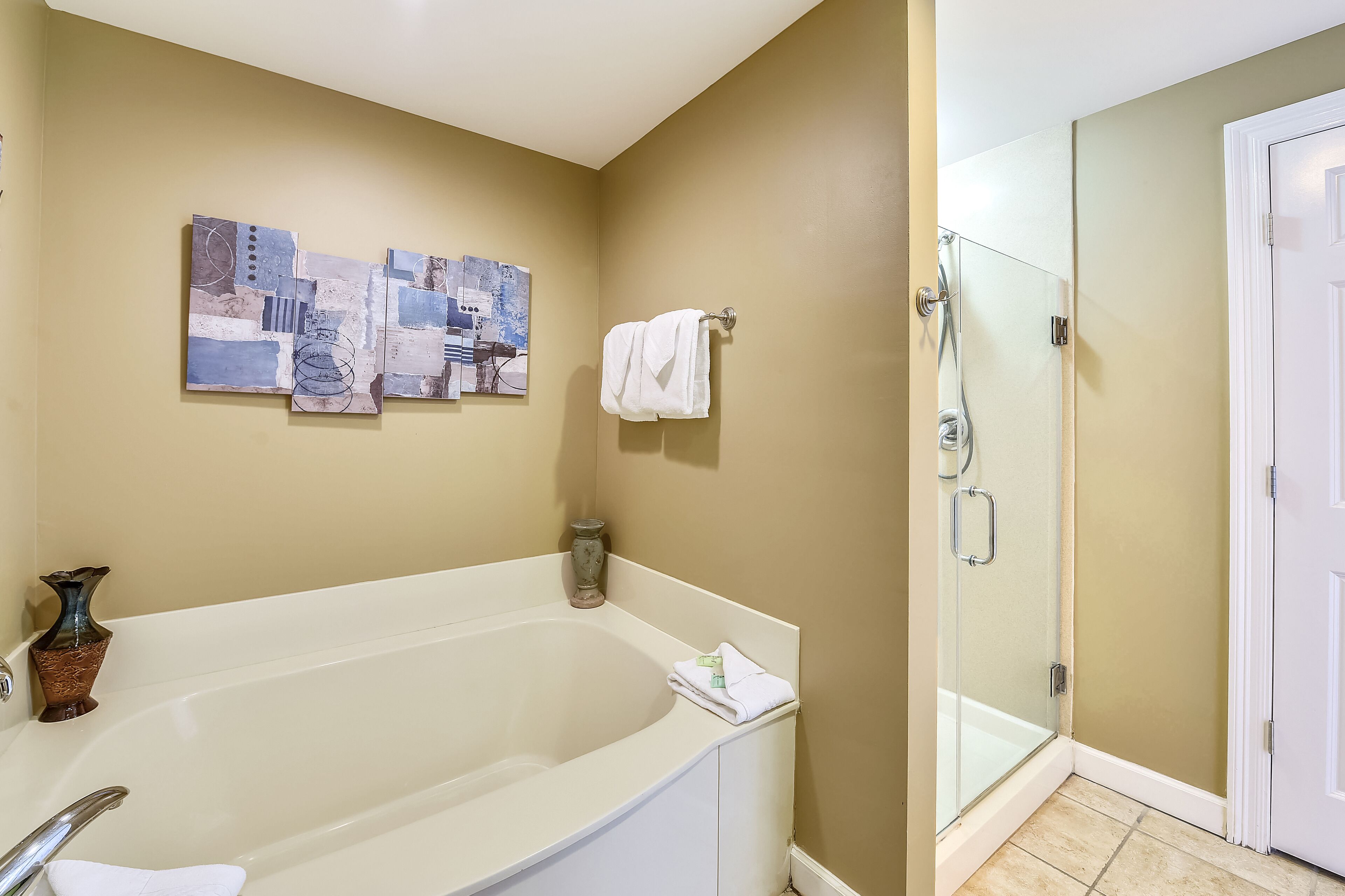 A bathroom with a bathtub, a glass shower enclosure, and a wall-mounted artwork.