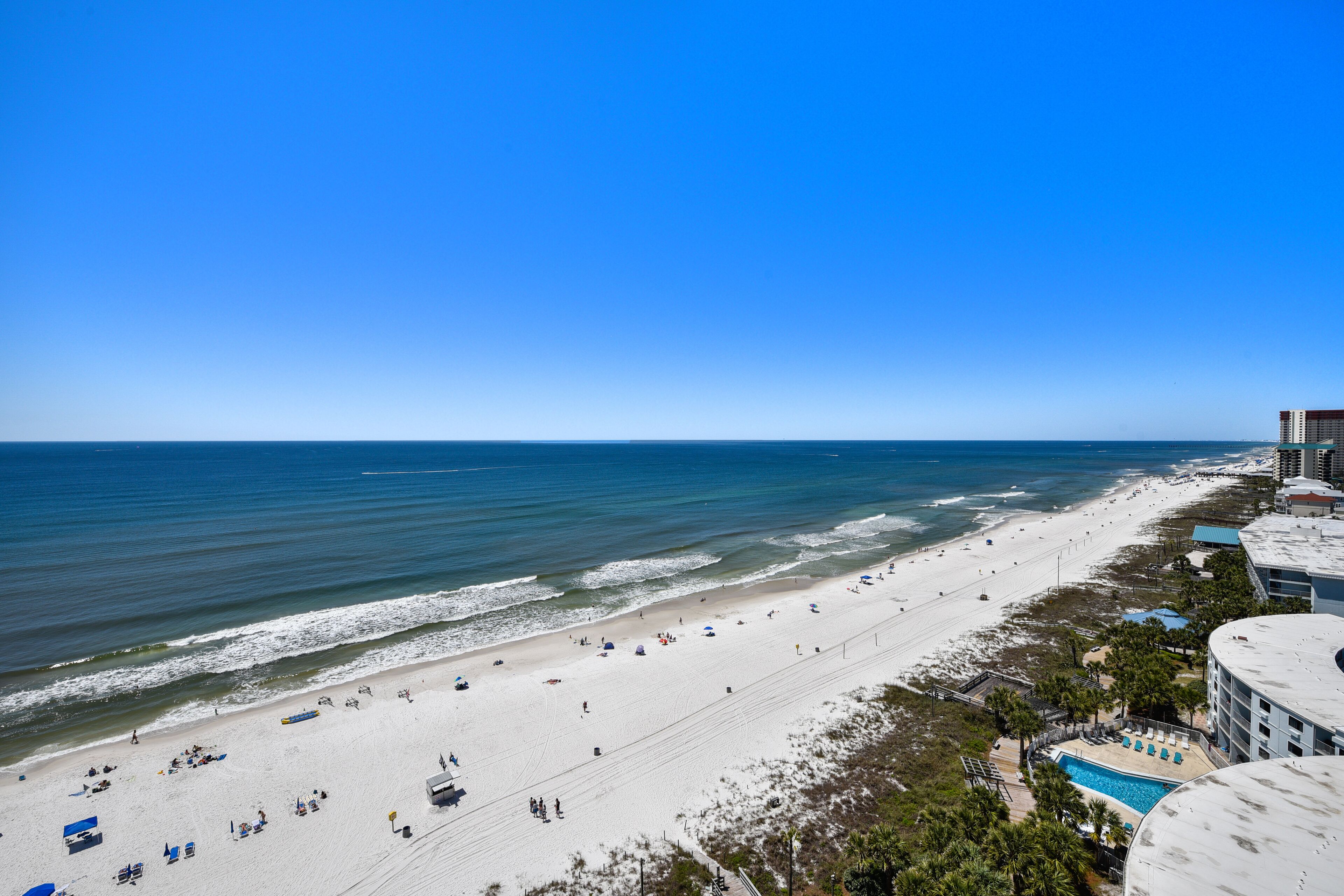 A beach with a swimming pool and a building with a flat roof.