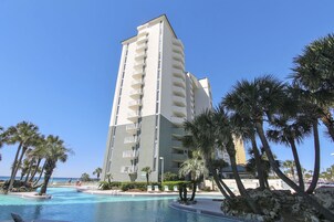 Un hotel alto con piscina y palmeras.