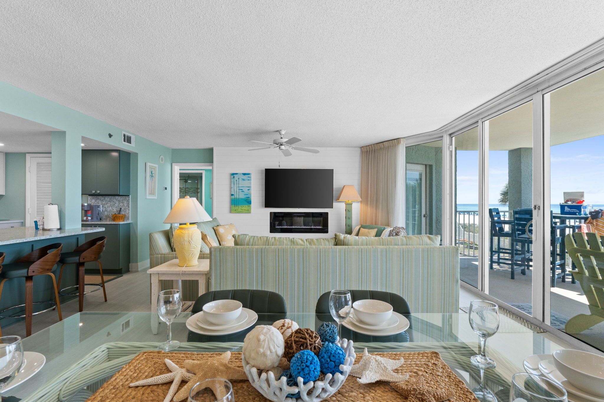 A modern hotel room with a balcony, a dining area, and a TV.