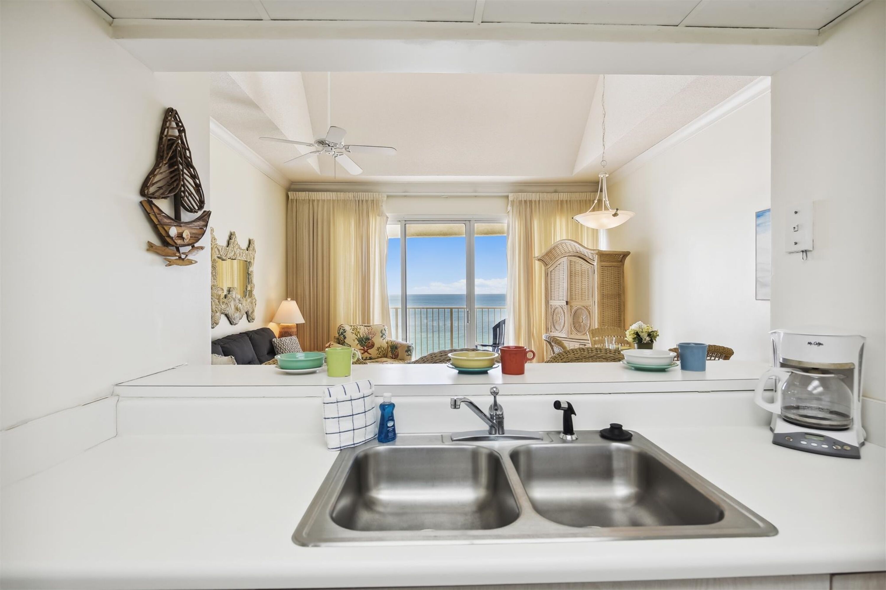 A modern kitchen with a large window, a ceiling fan, and a coffee maker.