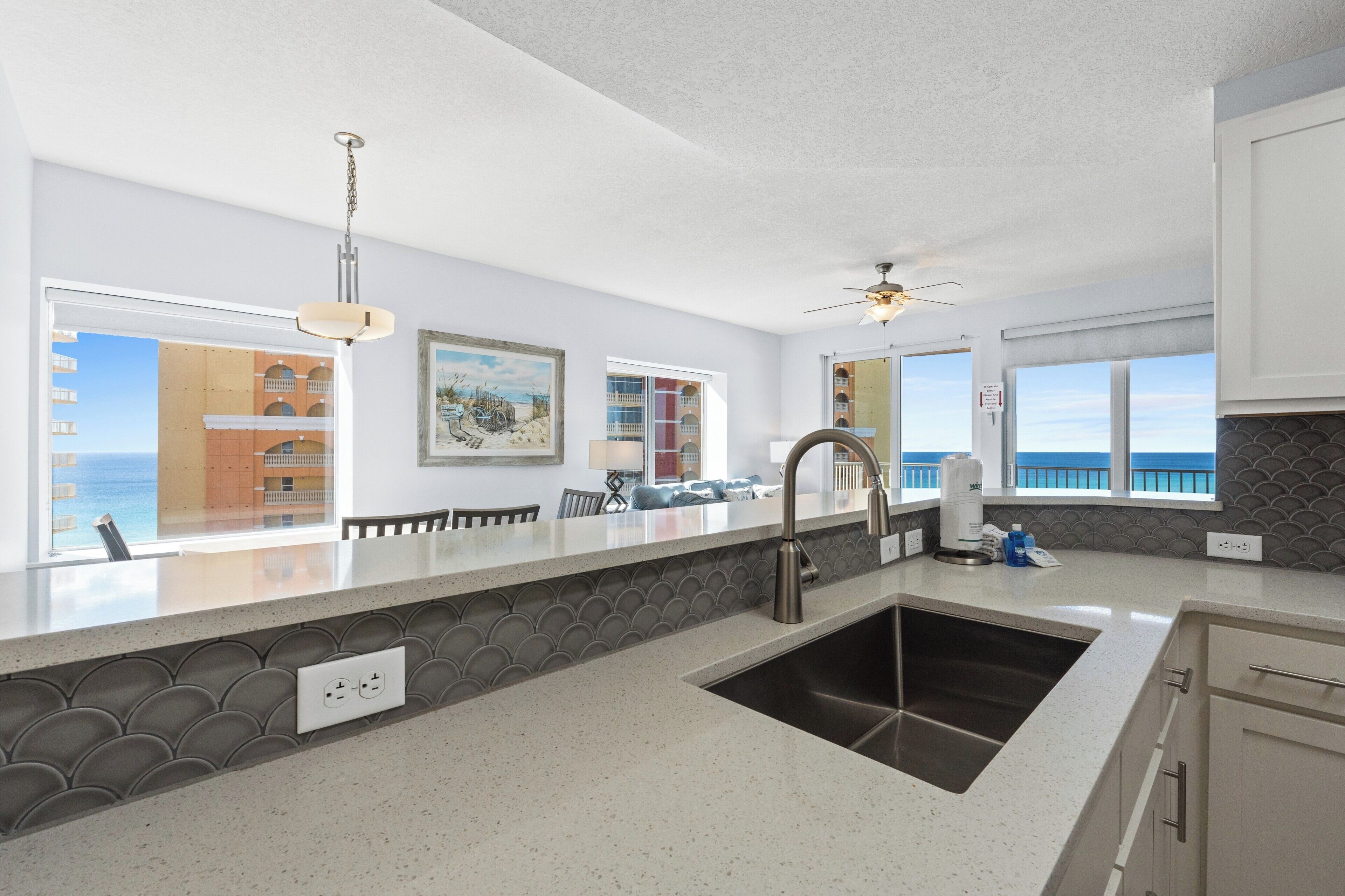 Una cocina moderna con una isla grande, un lavaplatos integrado y vistas al mar a través de las ventanas.