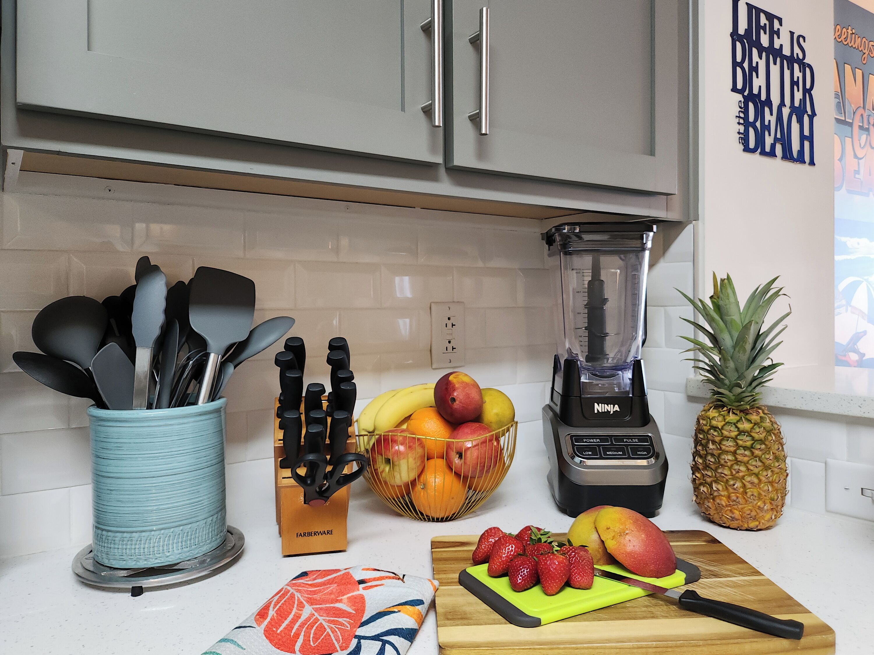 Uma bancada de cozinha com um liquidificador, frutas e utensílios.