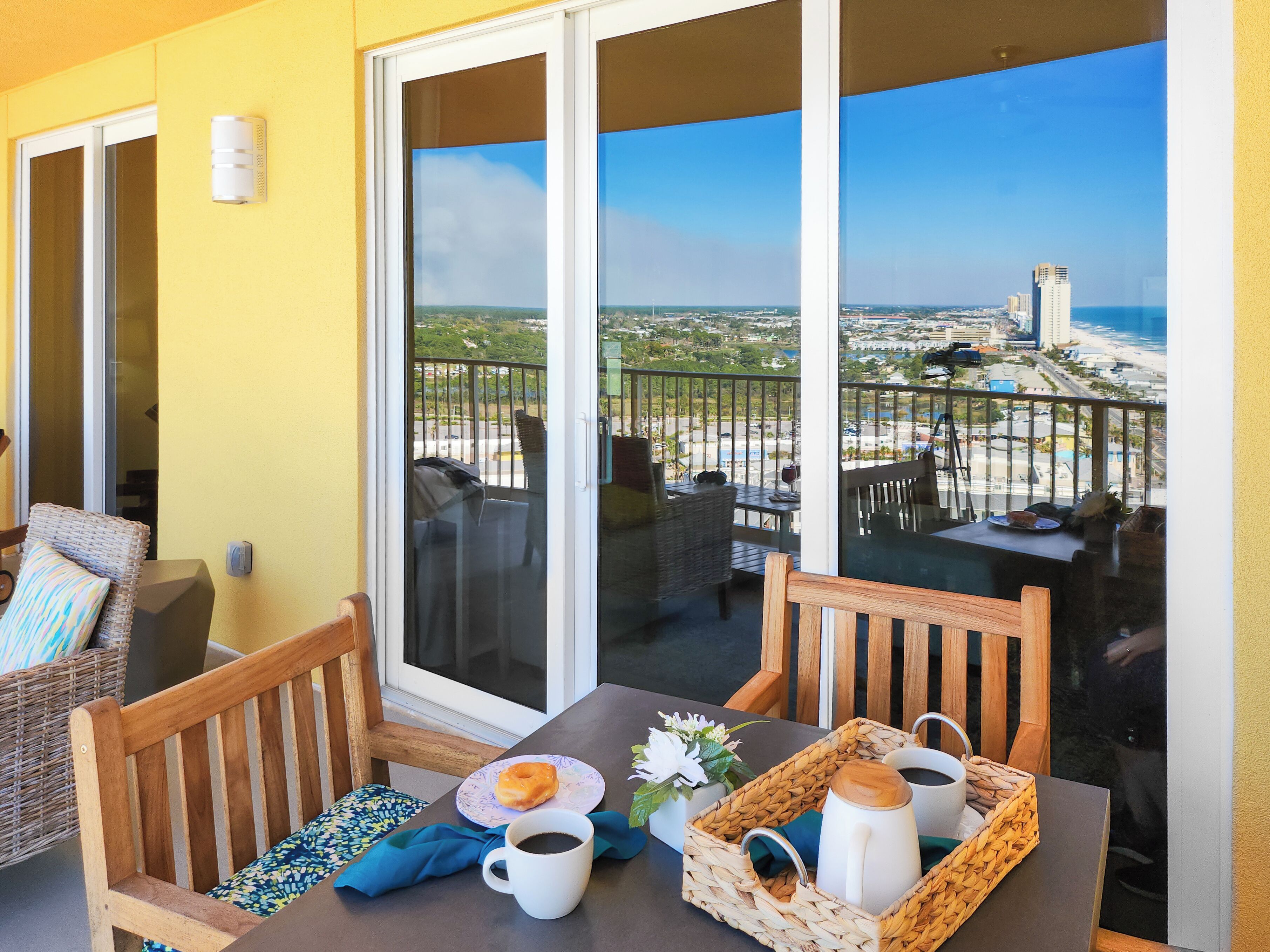 A balcony with wicker furniture, a table with a plate of food, a cup, and a basket.