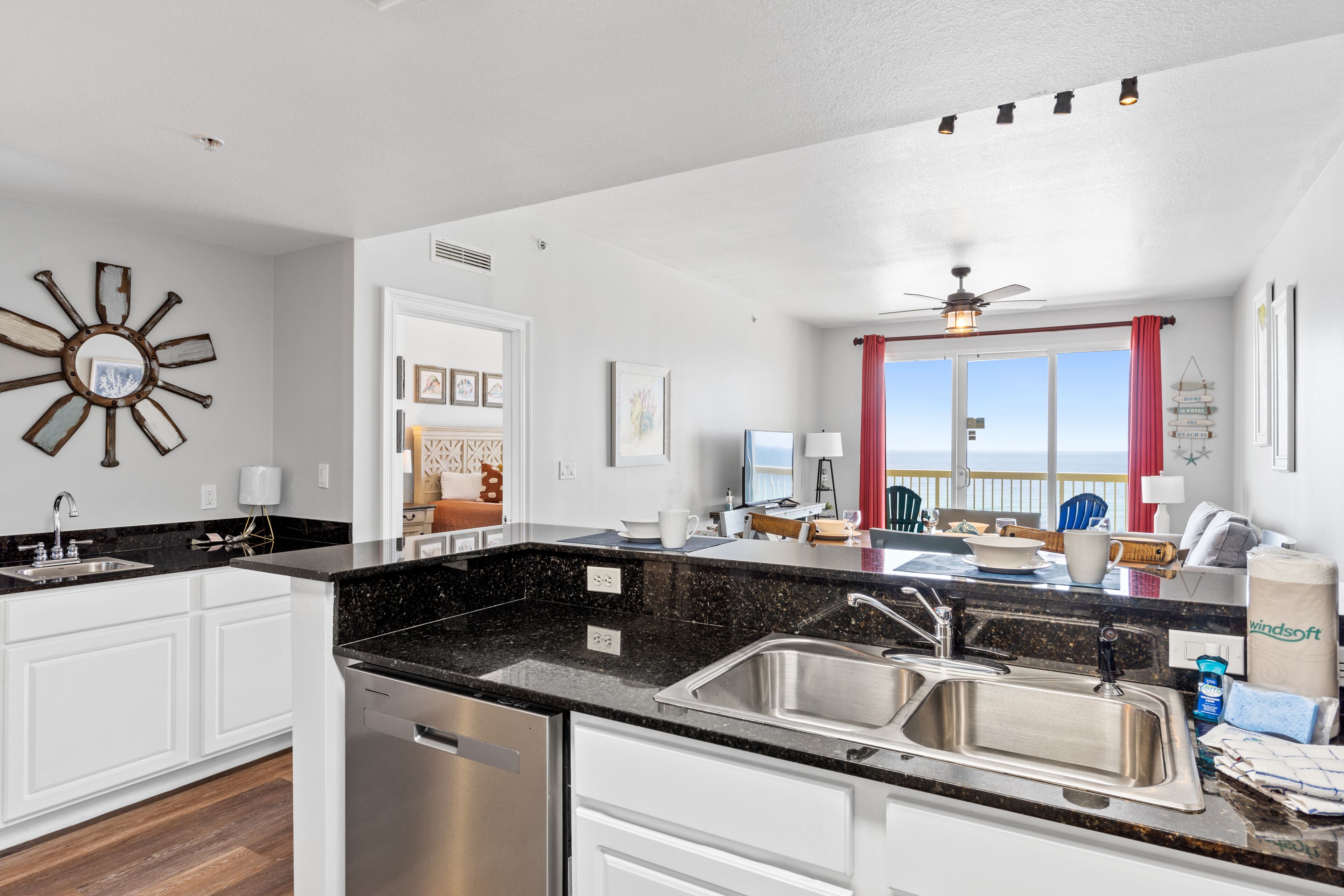 A modern kitchen with a black granite countertop, stainless steel sink, and white cabinetry.