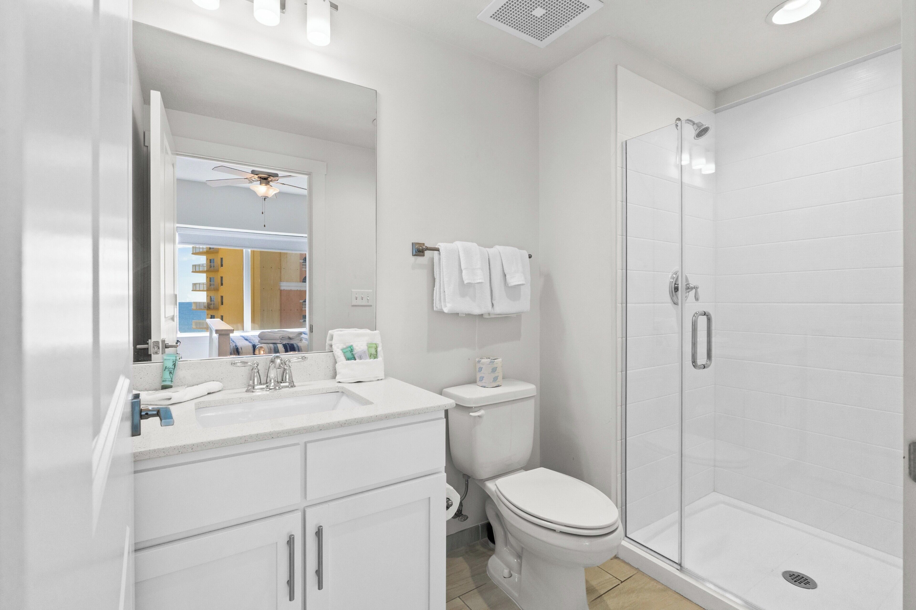 Une salle de bain moderne avec un lavabo, des toilettes et une douche, le tout de couleur blanche.
