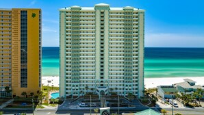 A high-rise hotel with a central atrium, a pool, and a view of the beach. - Celadon Beach Resort by Book That Condo (Panama City Beach)