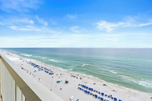 A beach with rows of blue umbrellas and lounge chairs, a sandy shore, and the ocean. - Celadon Beach Resort by Book That Condo (Panama City Beach)