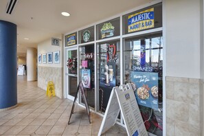 A storefront with various business signs, including a Starbucks and a market bar. - Majestic Beach Resort by Book That Condo (Panama City Beach)