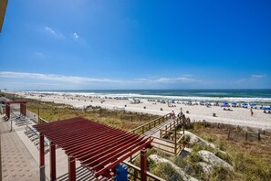 A beach with a wooden walkway leading to the shore, equipped with benches and a trash bin. - Majestic Beach Resort by Book That Condo (Panama City Beach)