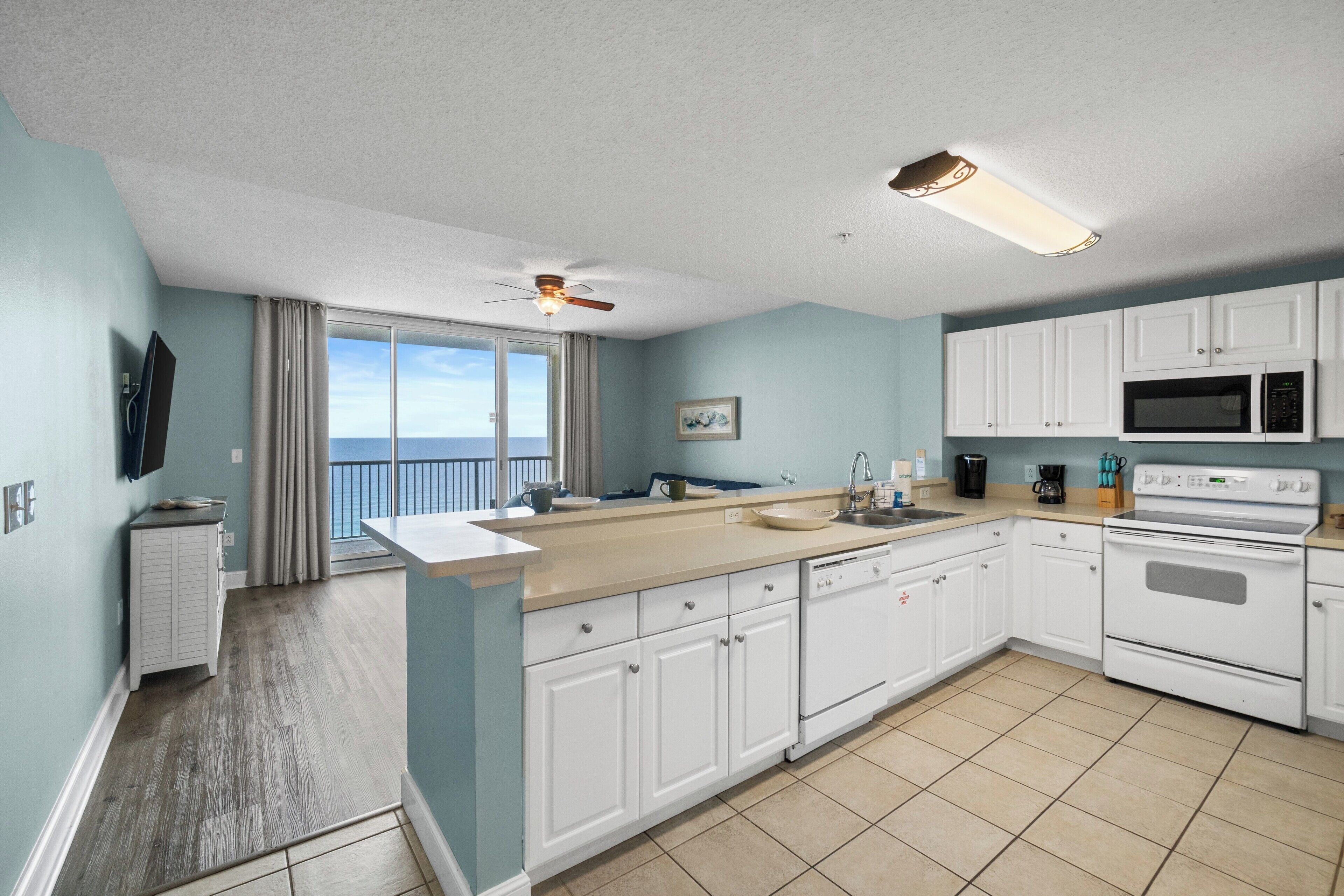 A modern kitchen with white cabinets, a large island, a microwave, and an oven.