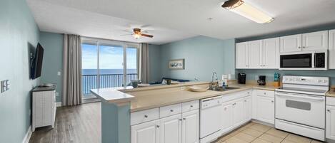 A modern kitchen with white cabinets, a large island, a microwave, and an oven.