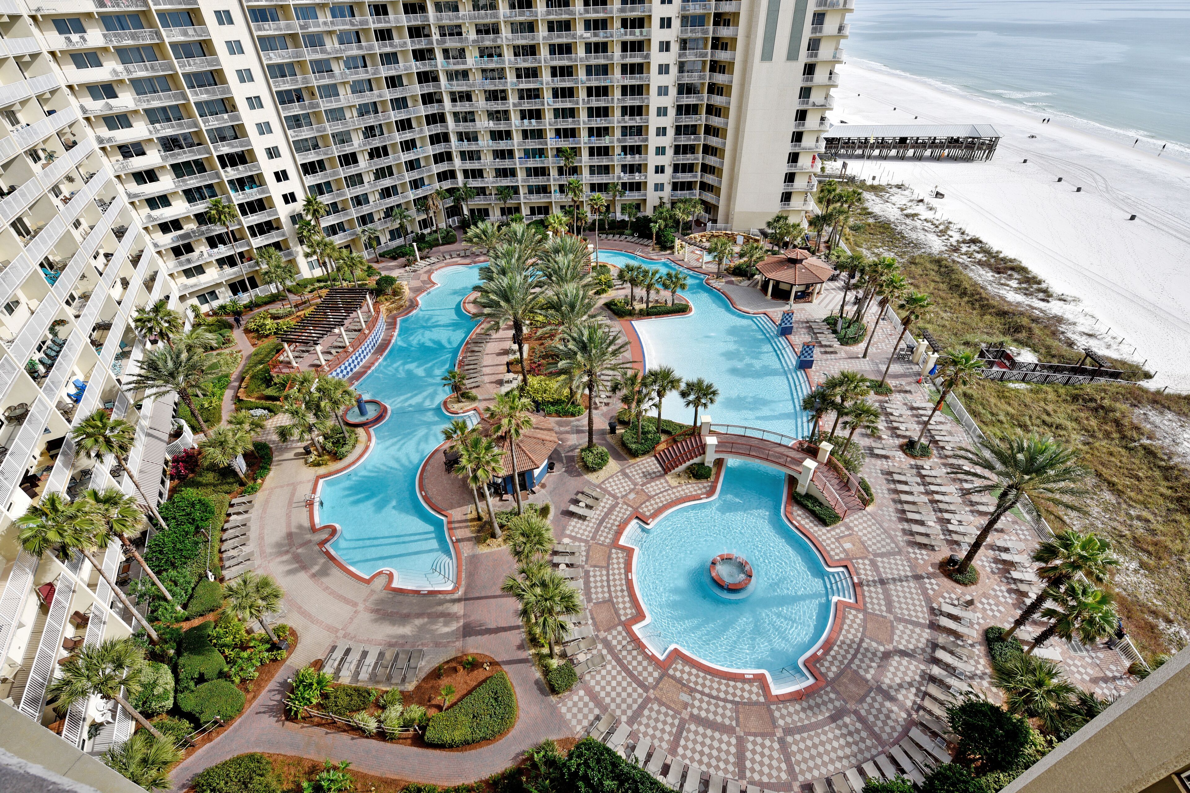 A resort with multiple swimming pools, palm trees, and a beach view.