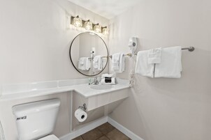 A bathroom with a toilet, sink, and a towel rack with multiple towels.